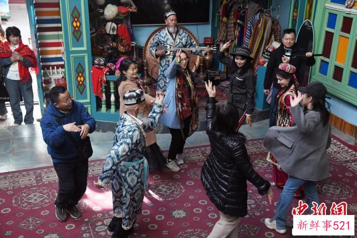 图为数名游客在喀什古城的网红打卡地和当地群众一起跳舞。　孙亭文 摄